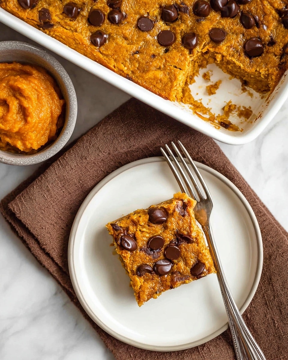 A close-up view of a baked oat square with chocolate chips on top, being lifted from a white baking dish with a metal spatula held by a woman's hand. The oat squares are golden brown with a rough, crumbly texture and scattered dark brown chocolate chips unevenly placed on the surface. The dish contains multiple oat squares, all evenly cut, sitting on a white marbled surface. In the blurred background, there is a small bowl with an orange spread or filling. The image captures the oat square’s dense, moist interior and crispy top layer photo taken with an iphone --ar 4:5 --v 7