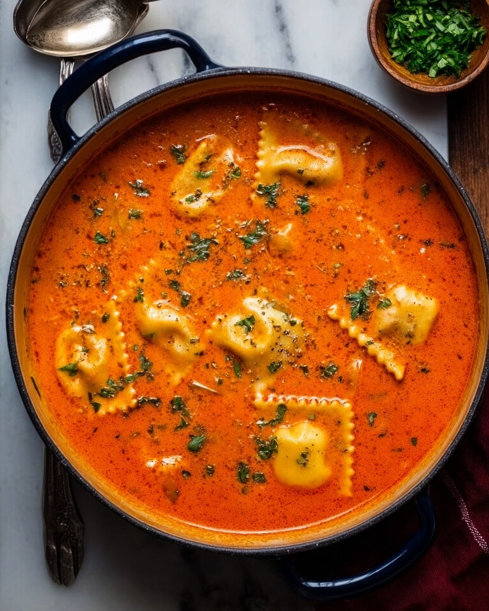 Two white bowls are filled with a thick tomato soup with a rich orange-red color and small green herbs scattered on top. Each bowl has three large, yellow ravioli pieces floating in the soup, showing a slightly soft texture with some edges visible. Small chunks of an unknown filling are resting on some ravioli, blending softly into the soup. Next to the bowls, a small wooden bowl holds finely chopped green herbs, adding a fresh contrast. The bowls are on a wooden surface, and two metal spoons rest on a dark cloth beside the front bowl. photo taken with an iphone --ar 4:5 --v 7