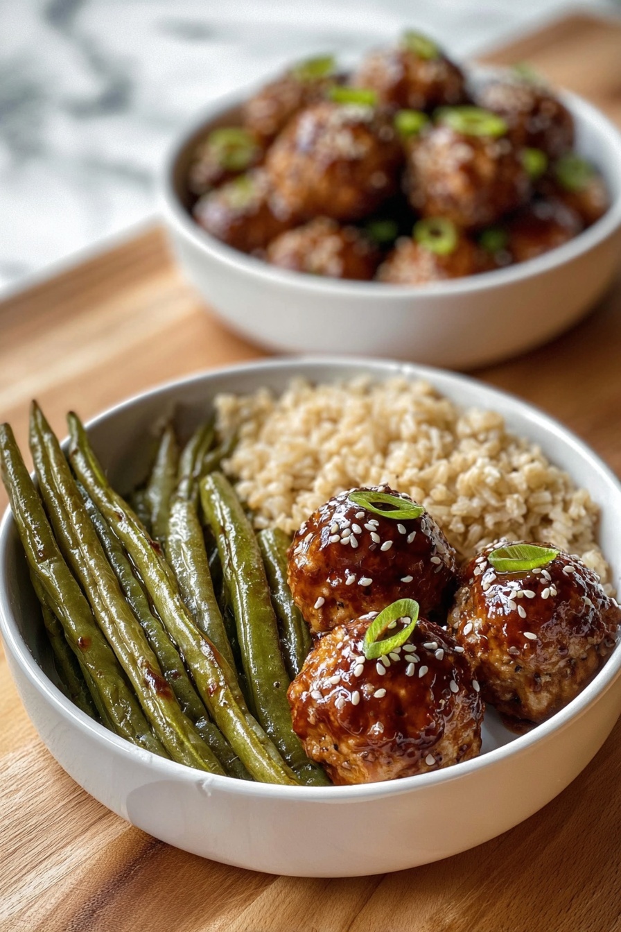 A white bowl contains three sections of food: on the left, a group of long, green roasted green beans with a slightly wrinkled texture; next to them at the bottom, a serving of light brown cooked rice with a soft, grainy look; on the right side, three round golden-brown meatballs covered with a shiny dark brown glaze, sprinkled with white sesame seeds and small green onion pieces on top. Behind this bowl, there is another white bowl filled with similar glazed meatballs, slightly blurred. Both bowls rest on a wooden surface with a white marbled texture background. Photo taken with an iphone --ar 2:3 --v 7 - Asian Glazed Turkey Meatballs, healthy turkey meatballs with Asian glaze, simple Asian meatball recipe, quick weeknight dinner ideas, savory turkey meatballs