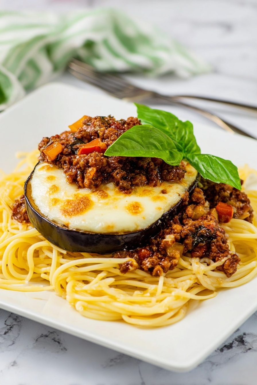 The dish shows a pile of yellow spaghetti noodles spread in a loose mound on a white square plate with rounded edges. On top of the noodles, there are slices of cooked eggplant with a glossy purple skin and soft interior, covered by a layer of melted, slightly browned white cheese. Between the eggplant layers, there are pieces of browned ground meat mixed with small bits of red tomatoes and mushrooms, adding texture and color. The top is garnished with fresh green basil leaves, adding a bright, leafy contrast. The plate sits on a white marbled surface with an orange and white striped cloth and a fork and knife placed behind it near the upper left edge. Photo taken with an iphone --ar 2:3 --v 7 - Eggplant Parmesan Spaghetti with Meat Sauce, Eggplant Parmesan spaghetti, Italian eggplant pasta, veggie pasta with meat sauce, hearty eggplant spaghetti