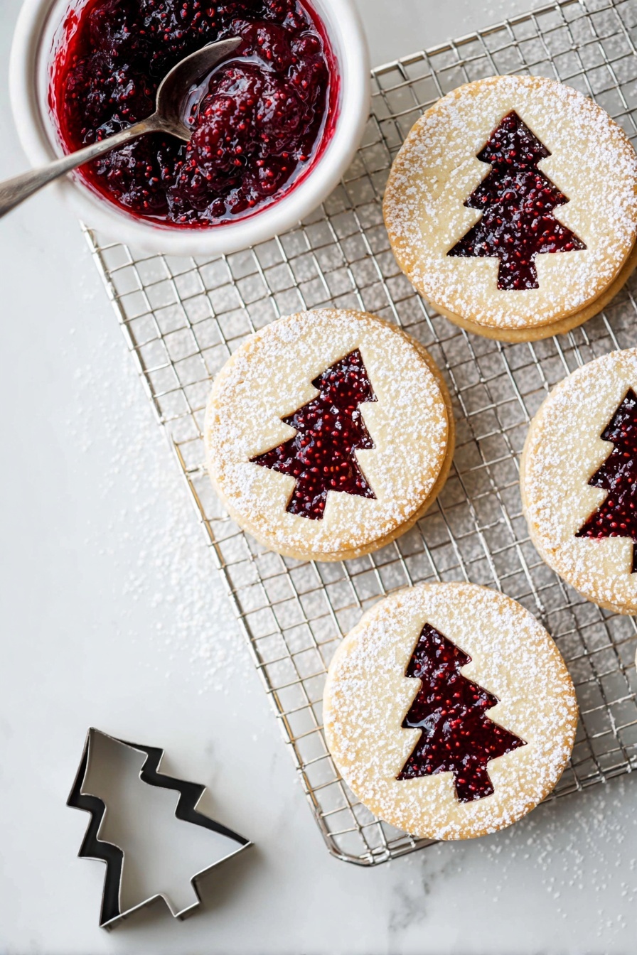 The image shows a cooling rack on a white marbled surface with four round layered cookies arranged on it and nearby. Each cookie has two layers: a light beige cookie base on the bottom, a layer of deep red raspberry jam in the middle, and a top cookie layer with a Christmas tree shape cut out, revealing the jam below. The top layer is dusted with white powdered sugar, creating a delicate snowy look. To the left of the rack is a small white bowl filled with thick, dark red raspberry jam with visible seeds, and a silver spoon inside. Near the bottom left corner, there is a small metal cookie cutter in the shape of a Christmas tree. photo taken with an iphone --ar 2:3 --v 7 - Raspberry Linzer Cookies, raspberry jam cookies, buttery Linzer cookies, holiday cookie recipes, jam-filled cookies