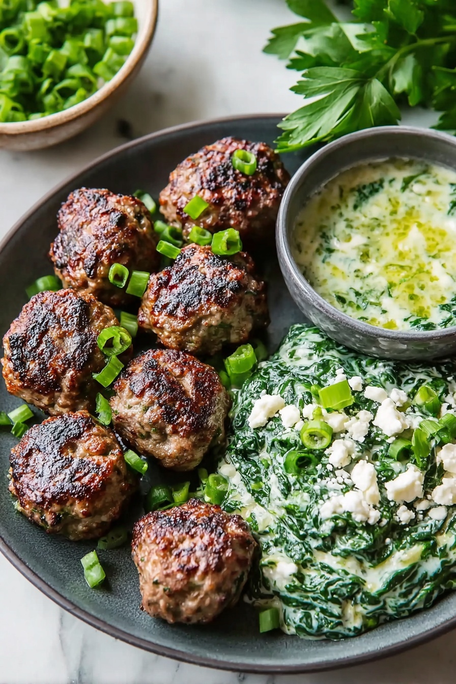 The image shows a dark gray plate with seven browned meatballs placed on the left side. On the right side of the plate, there is a creamy spinach mixture topped with chopped green onions and small white crumbles, likely cheese. Behind the plate, there is a small gray bowl filled with a greenish sauce that includes white chunks. Fresh green parsley leaves are visible in the background. The surface under the plate is a white marbled texture. photo taken with an iphone --ar 2:3 --v 7 - Spicy Lamb Meatballs with Green Herb Dip, lamb meatball recipes, spicy lamb dishes, herb dip recipes, easy lamb appetizer