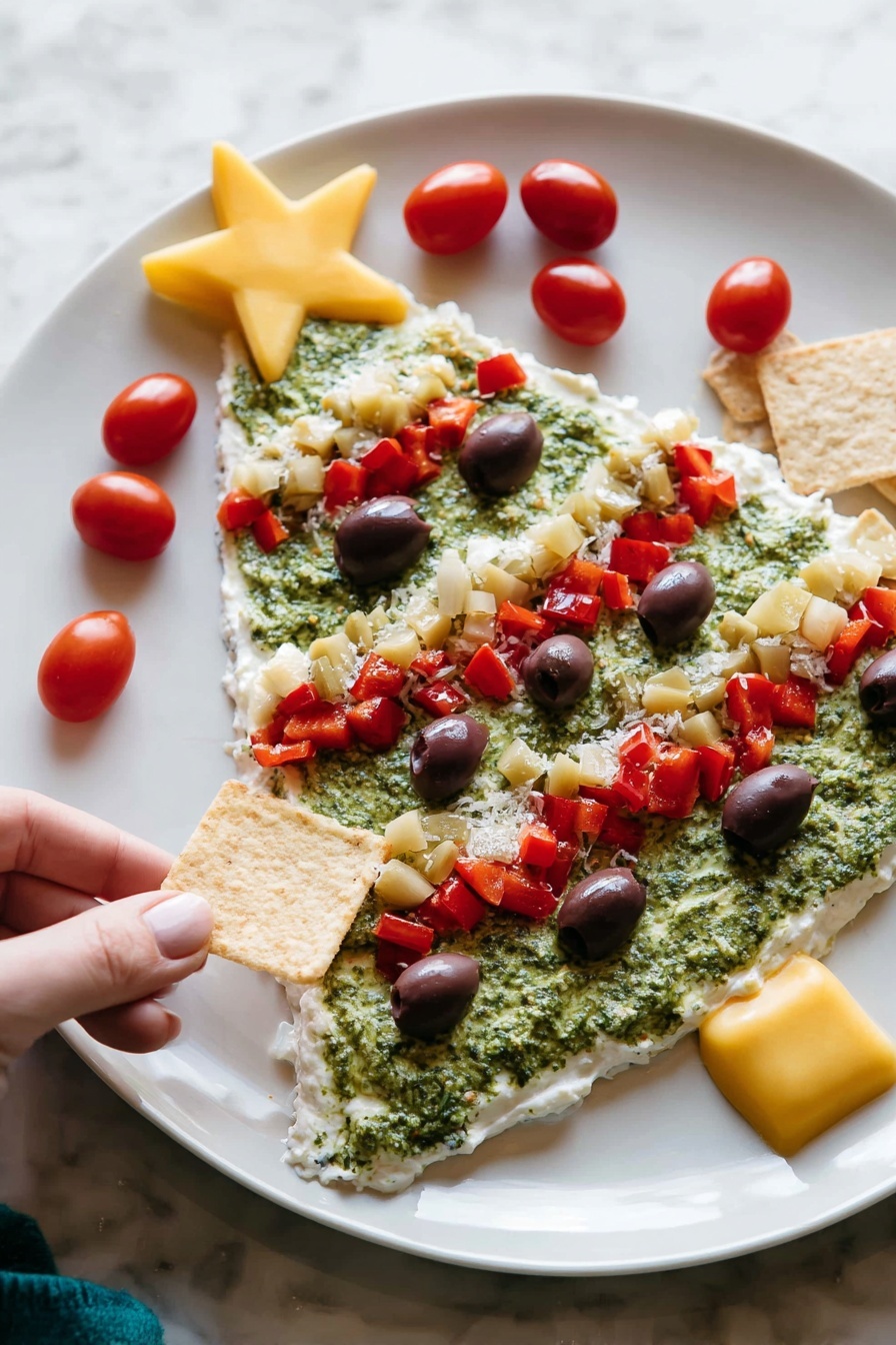 The image shows a white plate with a Christmas tree-shaped layered dip. The first layer is a smooth, white creamy base covering the entire tree shape. The second layer is a rough, green spread resembling pesto, filling most of the tree shape except the edges. On top, there are several red diced pepper pieces forming three diagonal lines across the tree. Small dark purple olive slices are scattered evenly over the green layer. There are small chunks of pale yellow artichoke hearts mixed in with the red peppers. Bright red cherry tomatoes decorate the edges, with a large yellow star-shaped piece placed at the top of the tree. A woman's hand is holding a square chip near the plate on a white marbled surface photo taken with an iphone --ar 2:3 --v 7 - Christmas Tree Bean Dip with Pesto, festive holiday appetizer, Christmas party dip, easy bean dip recipe, colorful holiday appetizer