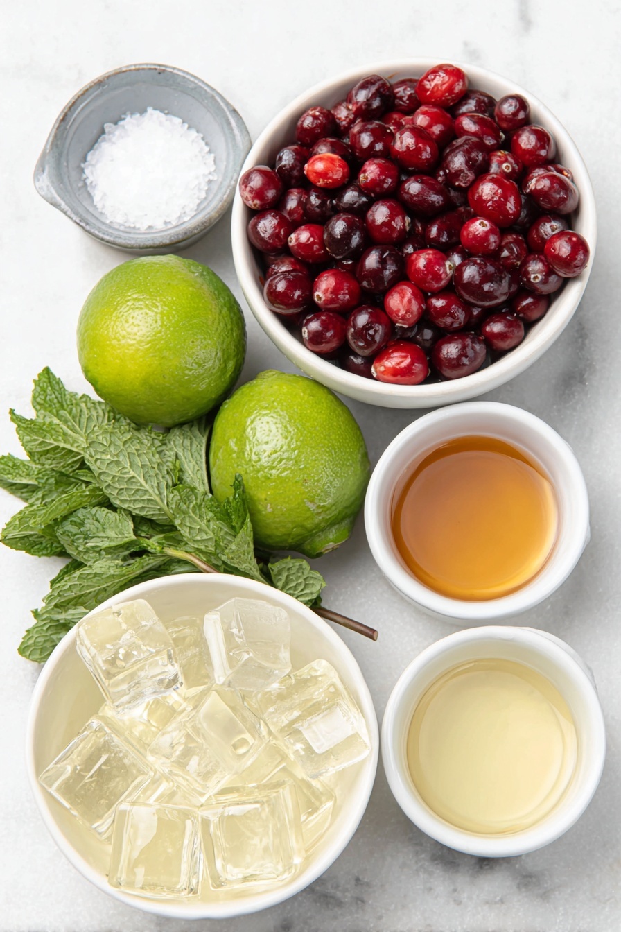 Flat lay of fresh green lime wedges, whole bright red cranberries, a few sprigs of vibrant fresh mint leaves, coarse crystals of salt in a small white ceramic bowl, clear ice cubes arranged neatly, and small white ceramic bowls each filled with pale golden tequila blanco, clear triple sec, fresh pale green lime juice, deep red cranberry juice, and light amber simple syrup, all ingredients naturally fresh and arranged in perfect symmetry on a clean white marble surface, soft natural light, photo taken with an iPhone, professional food photography style, fresh ingredients, white ceramic bowls, no bottles, no duplicates, no utensils, no packaging --ar 2:3 --v 7 --p m7354615311229779997 - Christmas Mistletoe Margarita, festive margarita recipes, holiday cocktail ideas, cranberry margarita, seasonal Christmas drinks
