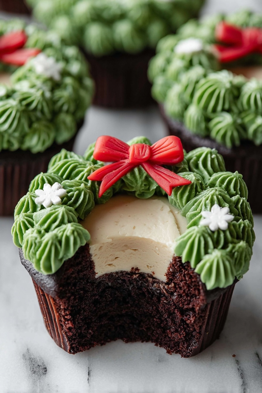 A chocolate cupcake with three visible layers is shown on a white marbled surface. The bottom layer is dark, moist chocolate cake, the middle layer is a smooth light cream filling, and the top layer is decorated with green frosting piped to look like leaves forming a wreath around the cream. A small red bow made of fondant sits at the top center of the green wreath, and tiny white flower-shaped decorations are placed on the green frosting. The cupcake is partially eaten, showing the inside layers clearly. Other similar cupcakes are blurred in the background. Photo taken with an iphone --ar 2:3 --v 7 - Chocolate Wreath Cupcakes with Buttercream Frosting, festive cupcake ideas, holiday cupcake recipes, chocolate cupcake wreath, colorful buttercream decorating