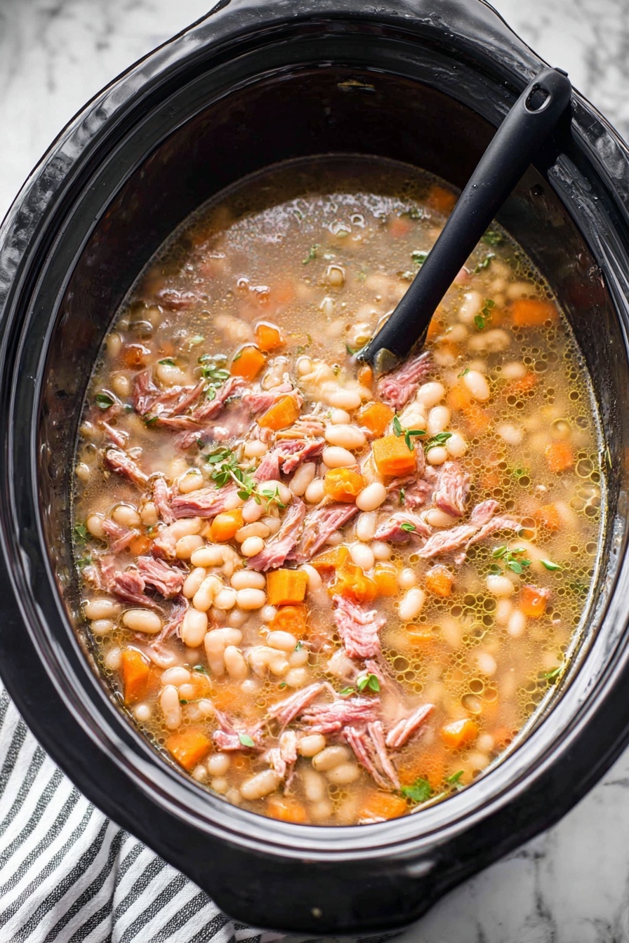 A large black slow cooker filled with a stew that has several layers and textures. The base layer shows a light brown broth with small bubbles of oil floating on top. Floating in the broth are many small, soft white beans, many small orange carrot cubes, and small bits of translucent onions. There are also shredded pieces of pinkish-brown cooked meat spread evenly throughout. Small green herbs are scattered on top, adding a fresh touch. A black spoon is partially submerged on the left side, resting inside the slow cooker. The slow cooker sits on a white marbled surface with a striped cloth partially visible below. Photo taken with an iphone --ar 2:3 --v 7 - Ham and Bean Soup, hearty ham and bean soup, easy ham and bean soup recipe, comforting bean and ham soup, simple ham and bean dinner