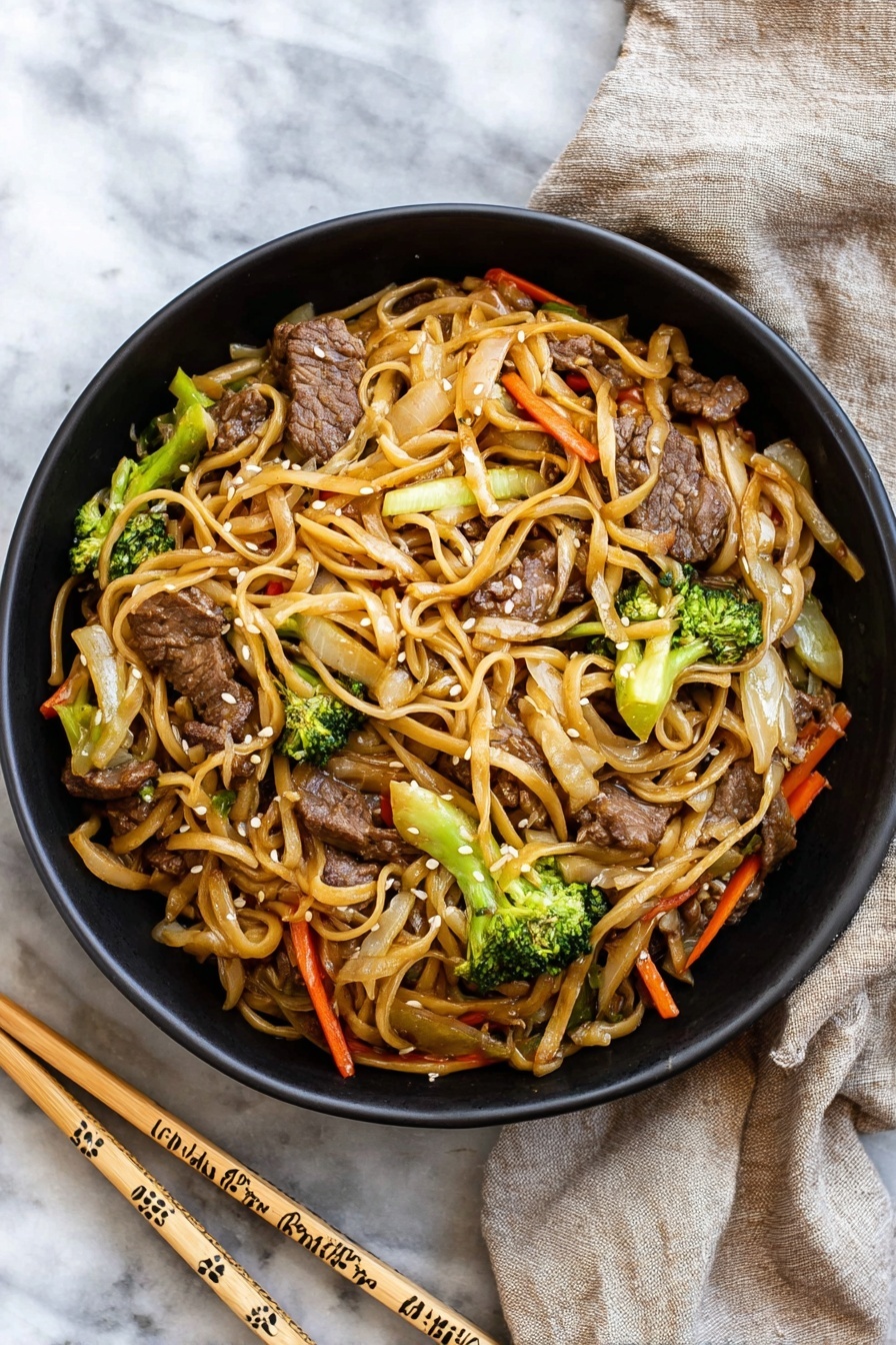 A black bowl filled with stir-fried noodles mixed with pieces of beef, bright green broccoli florets, thin orange carrot strips, and light brown cooked onions, all coated in a light sauce giving a slight shine; the noodles are long and a pale tan color, twisting through the vegetables and meat, garnished with small white sesame seeds. The bowl sits on a white marbled surface next to a pair of light wooden chopsticks decorated with simple patterns, and a beige cloth napkin is casually placed nearby. photo taken with an iphone --ar 2:3 --v 7 - Easy Beef Lo Mein, beef lo mein stir fry, quick homemade lo mein, savory beef noodle dish, Chinese beef noodles